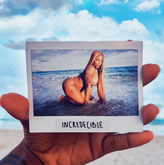 Instant photo print of a beach portrait held against the sky